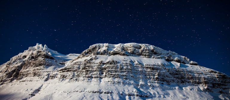 A mountain covered in snow under a night sky